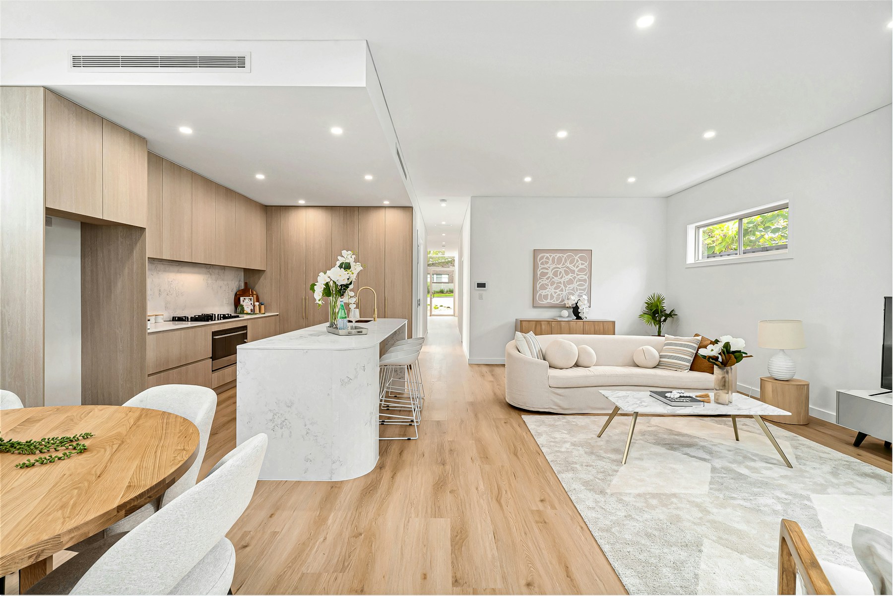 A bright living room opening onto a neatly arranged kitchen